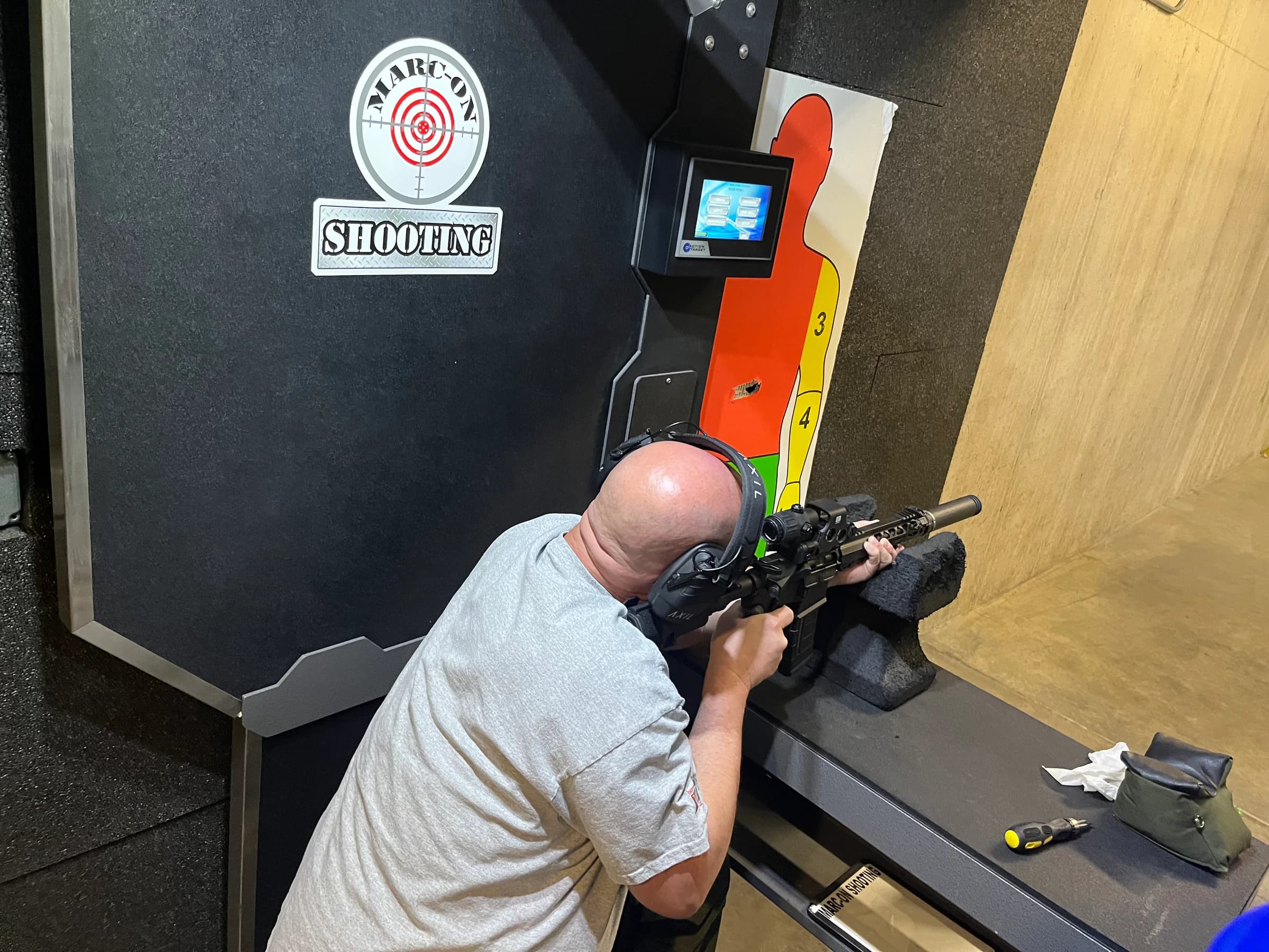 A shooter practicing with a rifle in a branded Marc-On range lane